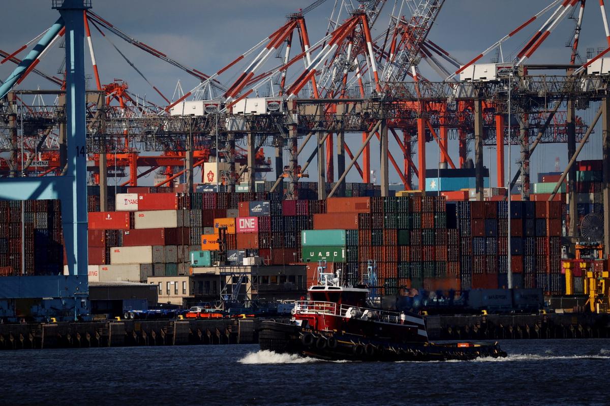 FILE PHOTO: A tugboat passes shipping containers being unloaded and stacked on a pier at Port Newark, New Jersey, U.S., November 19, 2021. REUTERS/Mike Segar/File Photo