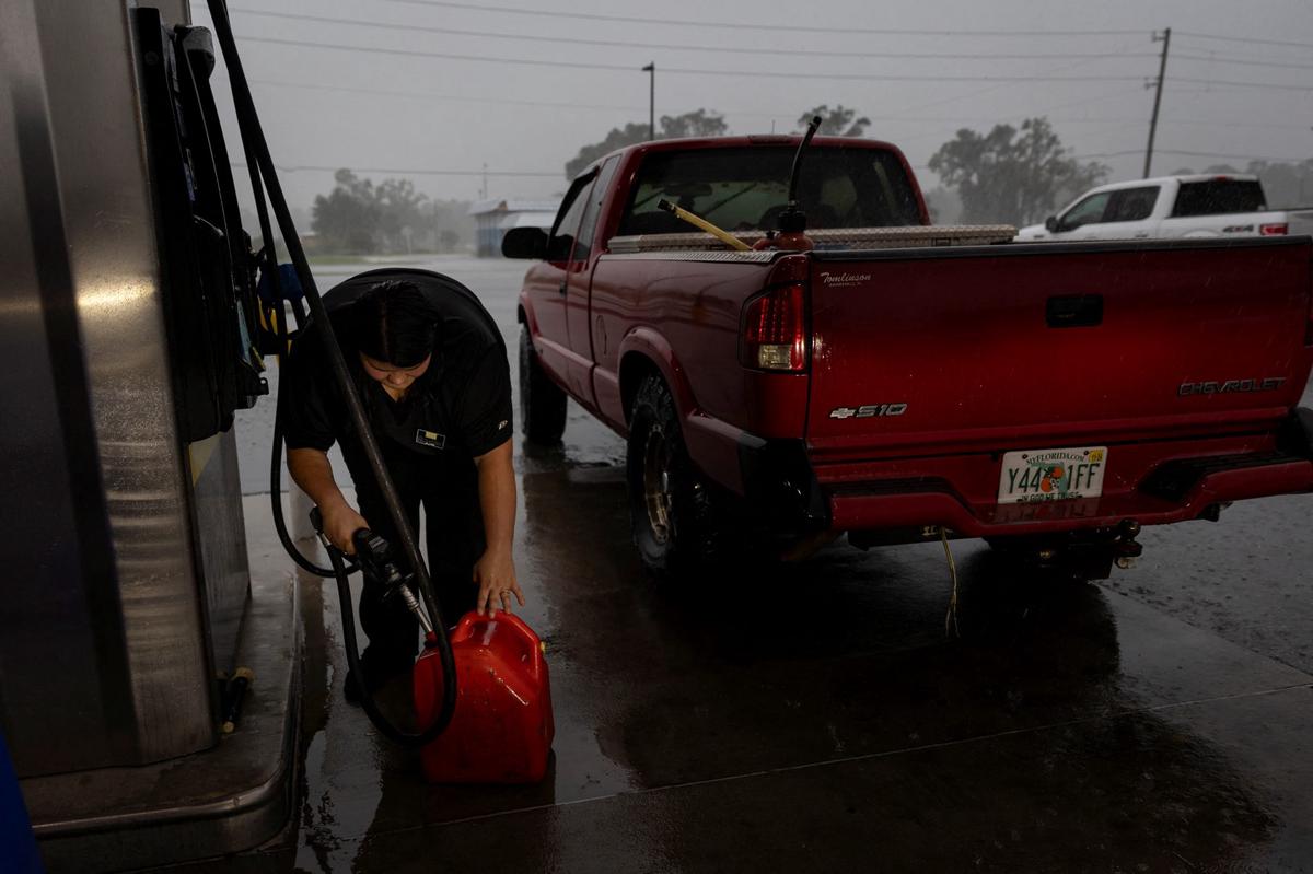 A woman fills up a container with gas as Hurricane Helene intensifies before its expected landfall on Florida’s Big Bend, in Cross City, Florida, U.S. September 25, 2024.  REUTERS/Marco Bello