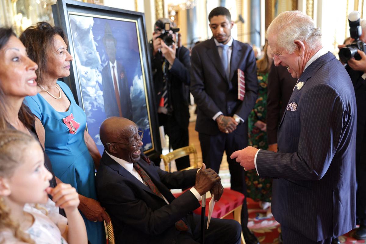 Britain's King Charles laughing with Delisser Bernard during a reception to mark the 75th anniversary of the arrival of HMT Empire Windrush to British shores, at Buckingham Palace on June 14, 2023 in London, Britain. During the reception to celebrate the Windrush Generation, ten portraits of Windrush elders were unveiled.     Chris Jackson/Pool via REUTERS