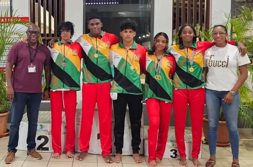 Members of the Guyana swim team, including the gold medal-winning Guyana 4x50m medley relay team of Vladimir Woodroffe (2nd from left), siblings Paul (3rd from left), and Patrice Mahaica (2nd from right), and Zara Crane display their spoils in the company of Director of Sport Steve Ninvalle (left) and NSC Vice Chairwoman Cristy Campbell (right).