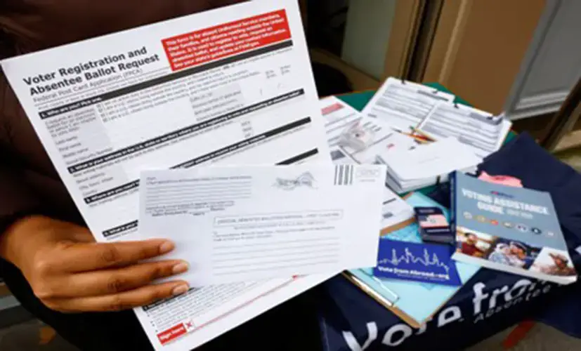 A U.S. citizen abroad voter holds a voter registration and absentee ballot request form and an envelope which will contain an official absentee balloting material at a stand set up outside a cafe by Democrats Abroad volunteers to help Americans living in Paris to navigate the bureaucracies of state and local election laws, in Paris, France, October 21, 2024.