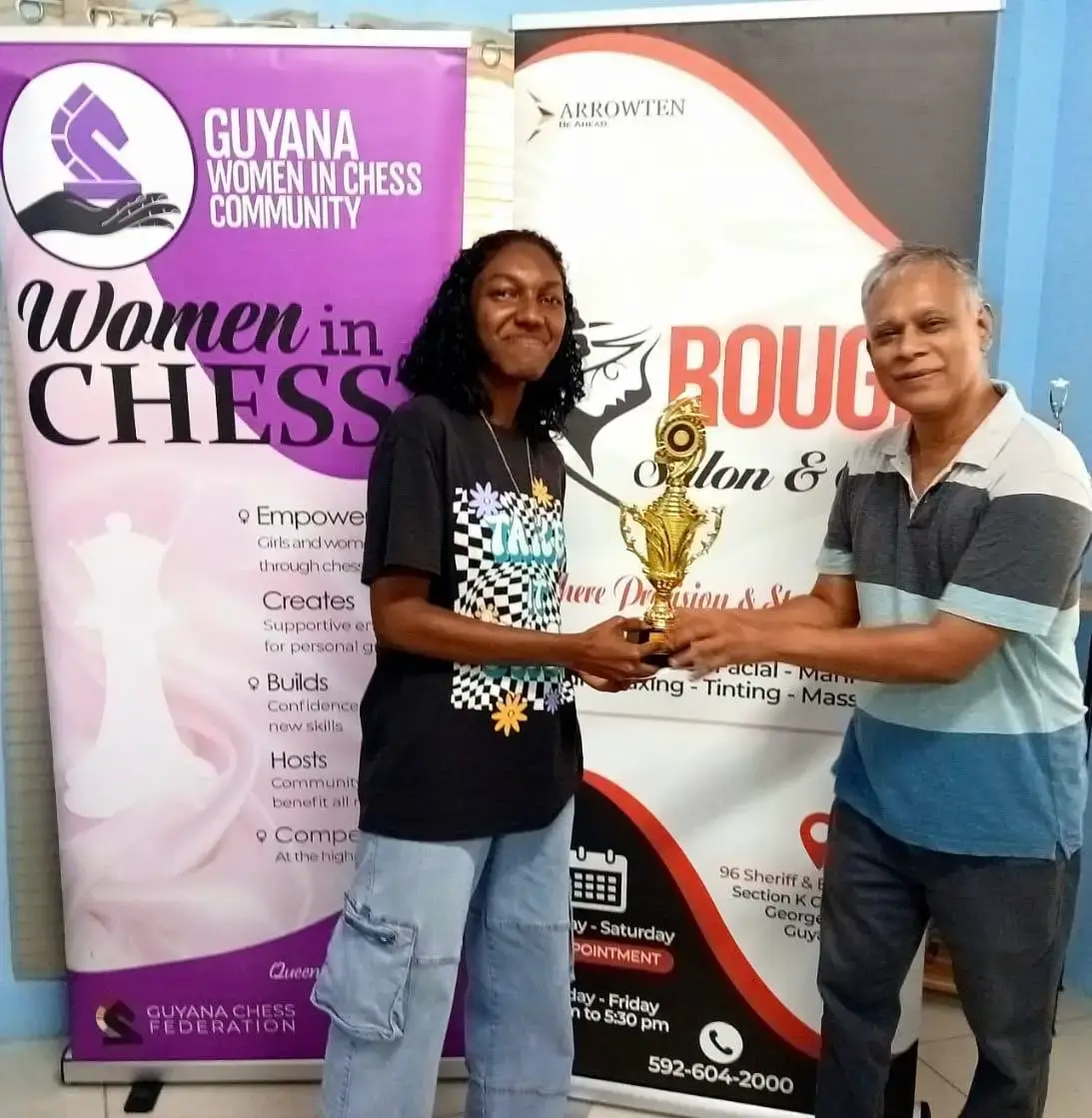 Jessica Callender (left) receives her prize after winning the Queenside Women’s One-Day Rapid Chess Championship.