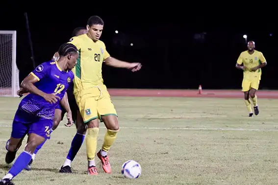 Golden Jaguars
forward Osaze De Rosario
(yellow) is
trying to
maintain
possession
while being
challenged by two Barbadian defenders (Jemima Holmes Photo).