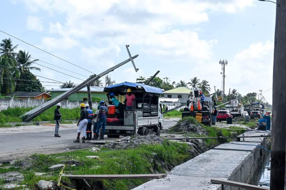 This Department of Public Information photo shows the leaning poles and  repair crews at work. Construction work is evident at the right of the photo.